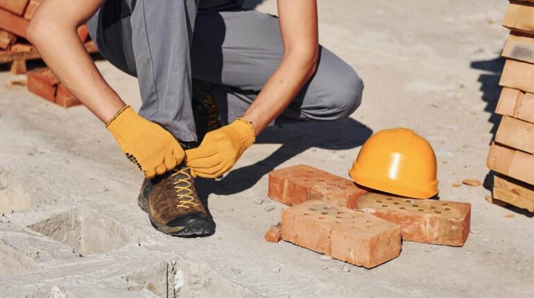 Pracownik budowy wiążący swoje buty robocze